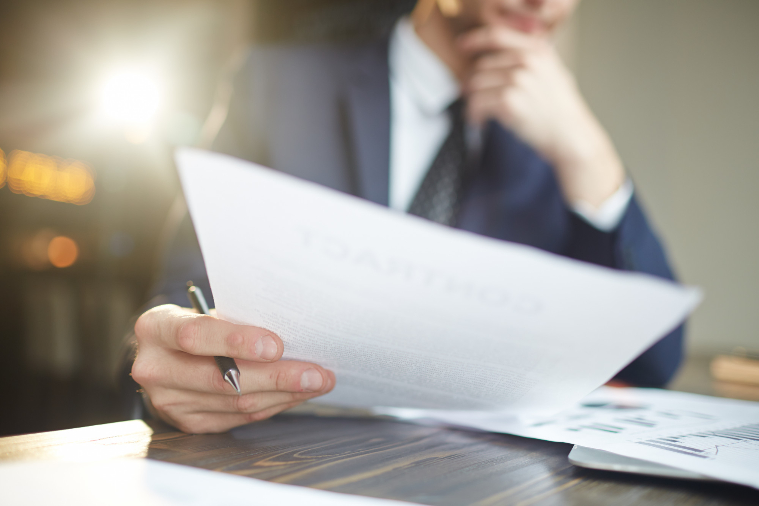 A man in a suit holding a piece of paper, possibly reading or presenting important information.